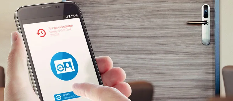 Smartphone mit Zutritts-App vor einer Hotelzimmertür mit elektronischem Beschlag