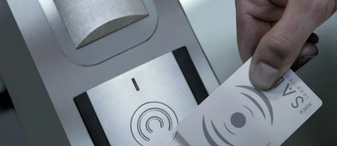 Hand hält eine Schlüsselkarte an einen elektronischen Türbeschlag